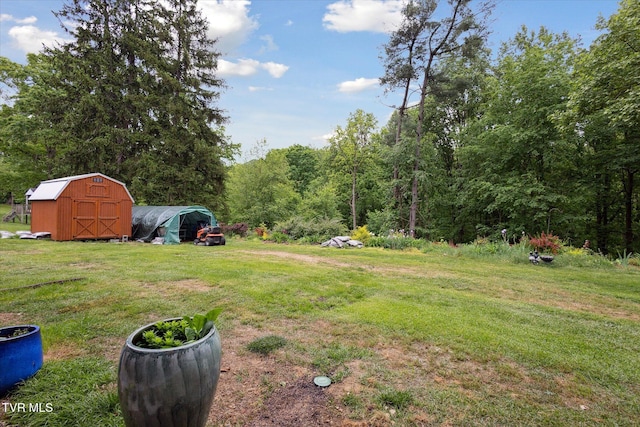 view of green lawn with a shed, an outdoor structure, and a forest view