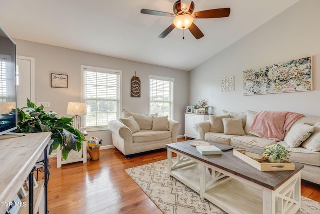living area with vaulted ceiling, hardwood / wood-style floors, a ceiling fan, and baseboards