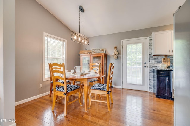 dining room with light wood-style flooring, baseboards, and lofted ceiling