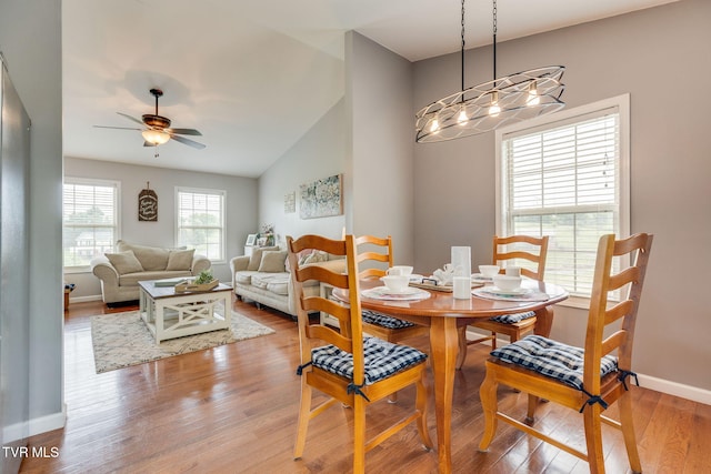 dining space featuring wood finished floors, baseboards, a ceiling fan, and lofted ceiling