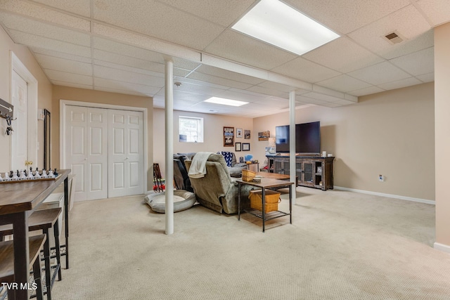 living area with carpet flooring, a paneled ceiling, and baseboards