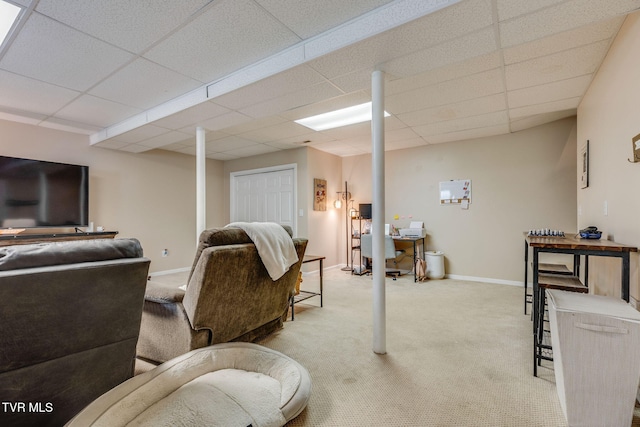 carpeted living area with a drop ceiling, baseboards, and a desk