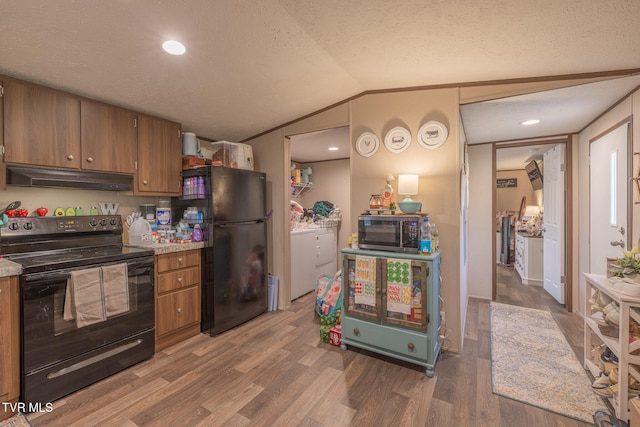 kitchen featuring black appliances, under cabinet range hood, brown cabinets, wood finished floors, and vaulted ceiling