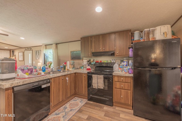 kitchen with black appliances, under cabinet range hood, brown cabinetry, light wood-type flooring, and a textured ceiling