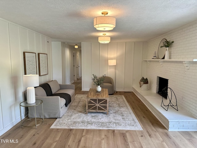 8467 Rich Valley Rd, Bristol, VA 24202 - living room featuring a decorative wall, a textured ceiling, wood finished floors, brick wall, and a fireplace