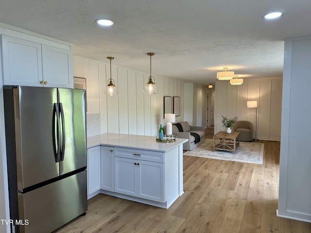 8467 Rich Valley Rd, Bristol, VA 24202 - kitchen with freestanding refrigerator, a peninsula, open floor plan, light wood-style flooring, and decorative light fixtures