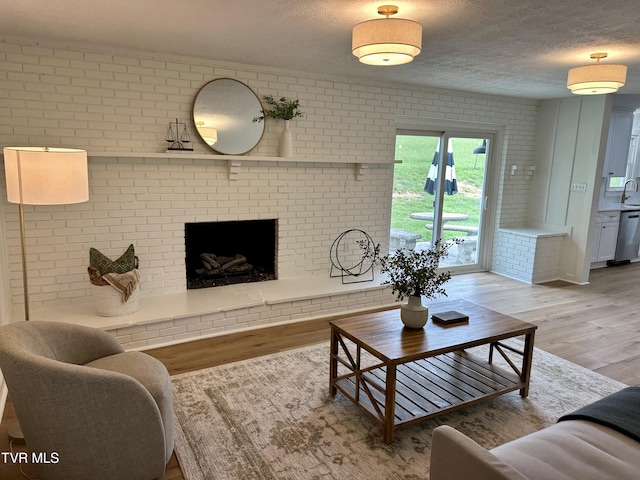 8467 Rich Valley Rd, Bristol, VA 24202 - living room with light wood-style flooring, brick wall, a textured ceiling, and a fireplace