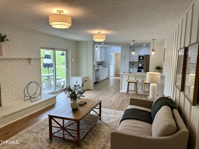 8467 Rich Valley Rd, Bristol, VA 24202 - living area with a textured ceiling, brick wall, and light wood-style flooring