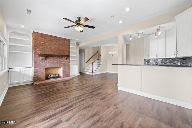 15127 Stonewall Rdg, Bristol, VA 24202 - unfurnished living room featuring a chandelier, a ceiling fan, a brick fireplace, stairway, and dark wood-style flooring