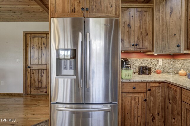 138 Ray Cemetery Rd, Roan Mountain, TN 37687 - kitchen featuring stainless steel fridge with ice dispenser, wood finished floors, tasteful backsplash, brown cabinetry, and baseboards