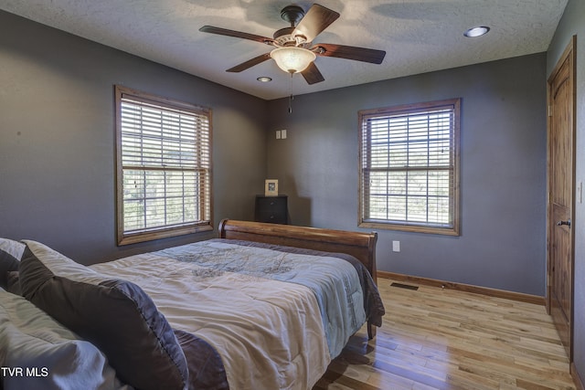 138 Ray Cemetery Rd, Roan Mountain, TN 37687 - bedroom featuring baseboards, a textured ceiling, light wood-type flooring, multiple windows, and a ceiling fan