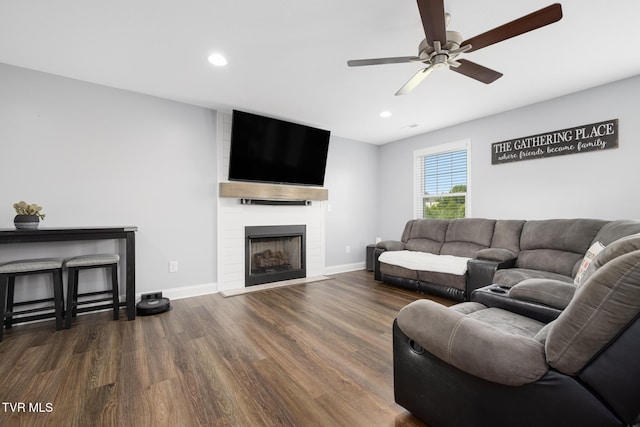 living room featuring a ceiling fan, wood finished floors, baseboards, recessed lighting, and a large fireplace
