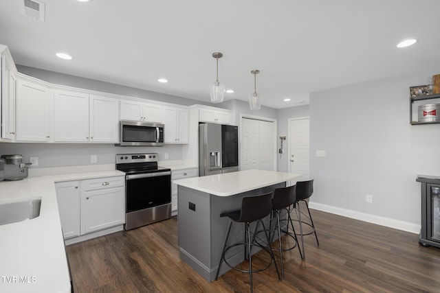kitchen featuring appliances with stainless steel finishes, dark wood-style floors, a kitchen bar, recessed lighting, and white cabinets
