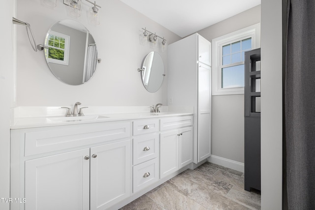 bathroom featuring baseboards and double vanity
