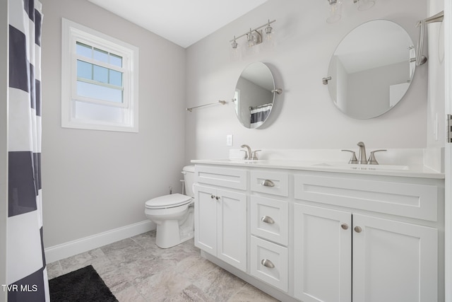 full bathroom featuring toilet, baseboards, and double vanity