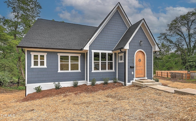 view of front of property featuring roof with shingles and fence