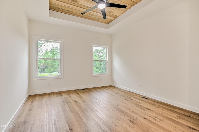 unfurnished room featuring a tray ceiling, wooden ceiling, a ceiling fan, light wood-style floors, and baseboards
