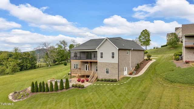 rear view of property featuring stairway, a lawn, a sunroom, and a patio