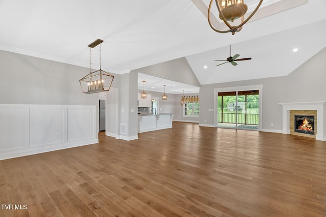 unfurnished living room featuring a chandelier, lofted ceiling, a glass covered fireplace, wood finished floors, and recessed lighting