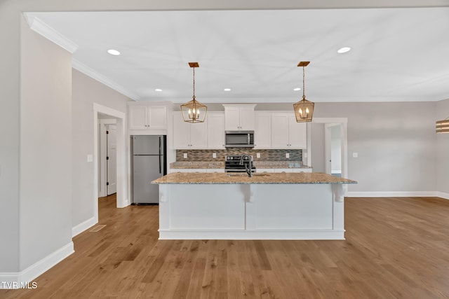kitchen with stainless steel appliances, white cabinets, baseboards, backsplash, and a center island with sink