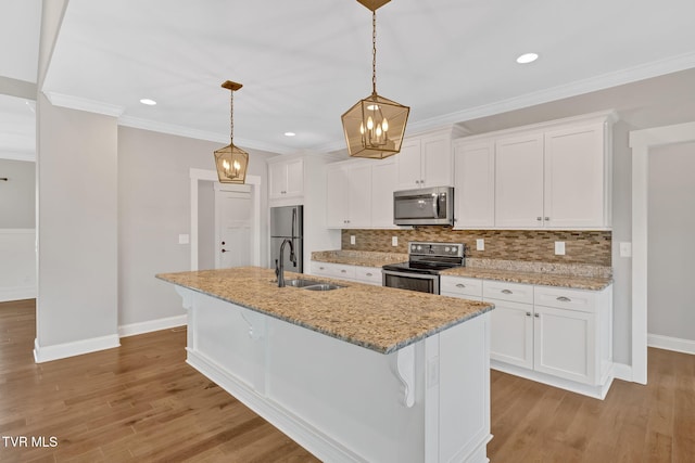 kitchen featuring stainless steel appliances, a sink, baseboards, a kitchen island with sink, and white cabinetry