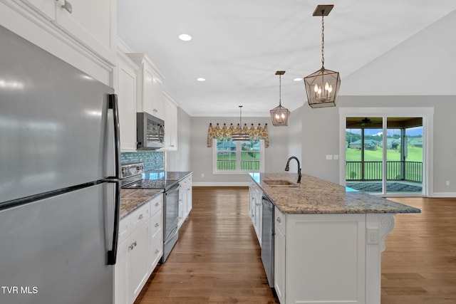 kitchen with stainless steel appliances, a sink, white cabinetry, baseboards, and stone counters