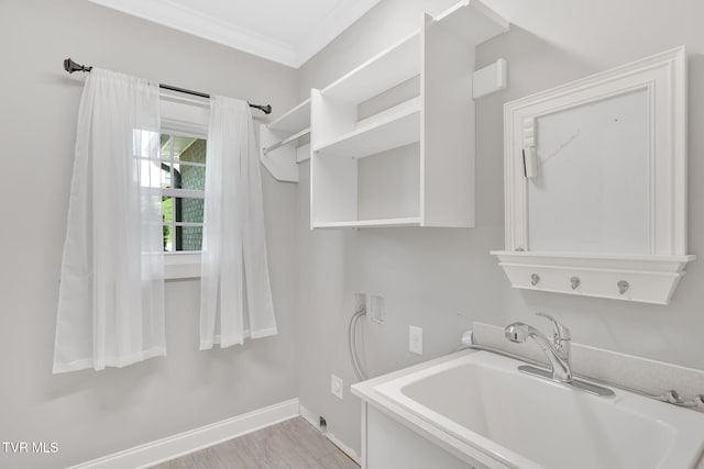 washroom featuring hookup for a washing machine, crown molding, light wood finished floors, and baseboards