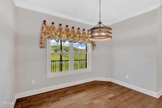 unfurnished dining area featuring a chandelier, baseboards, crown molding, and wood finished floors