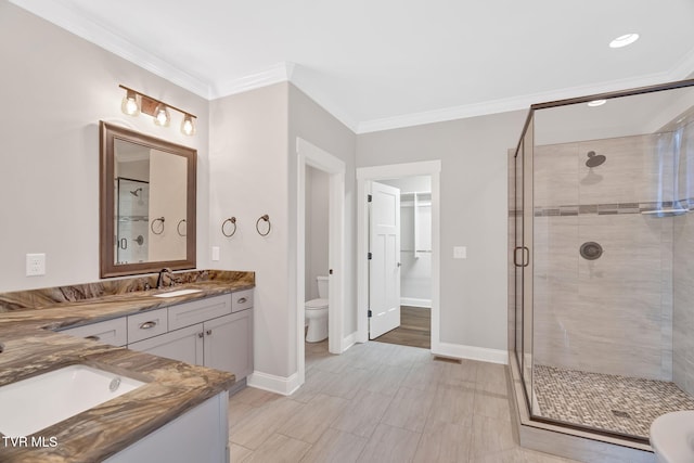 full bathroom featuring a shower stall, toilet, ornamental molding, baseboards, and vanity