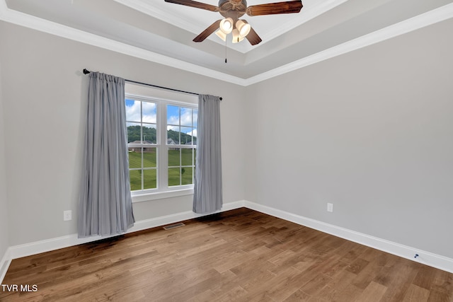 spare room featuring wood finished floors, ornamental molding, ceiling fan, and baseboards