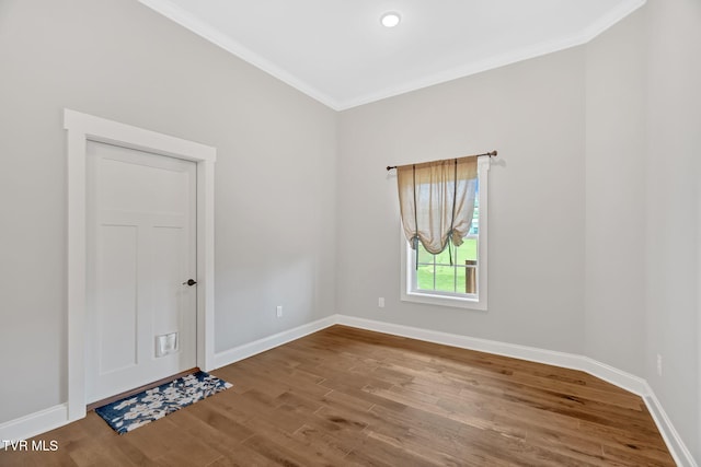 empty room with crown molding, wood finished floors, and baseboards