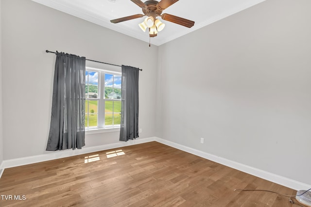 empty room featuring baseboards, wood finished floors, a ceiling fan, and ornamental molding