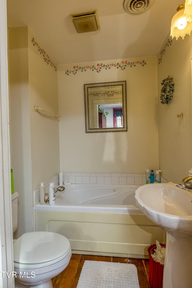 full bath featuring a bath, toilet, and wood finished floors