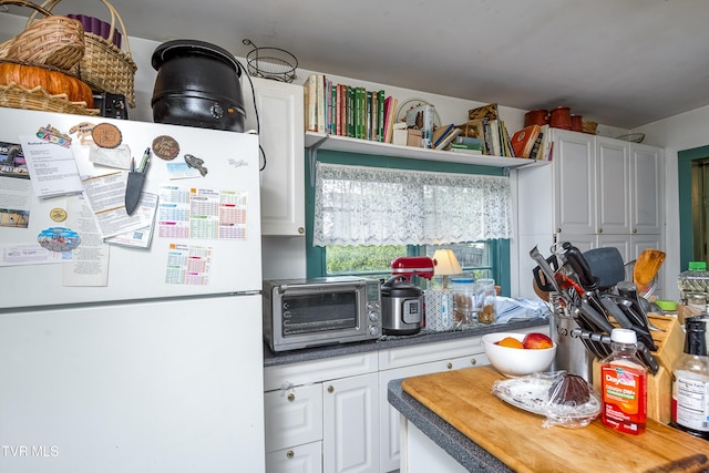 kitchen with freestanding refrigerator, white cabinets, and wood counters