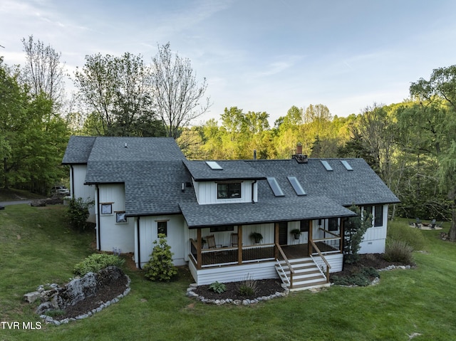 rear view of house featuring a shingled roof, a chimney, a lawn, and a porch