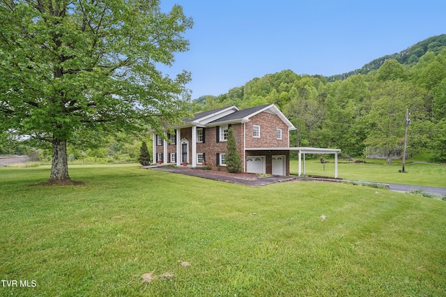view of front of property featuring driveway, an attached garage, brick siding, a view of trees, and a front lawn