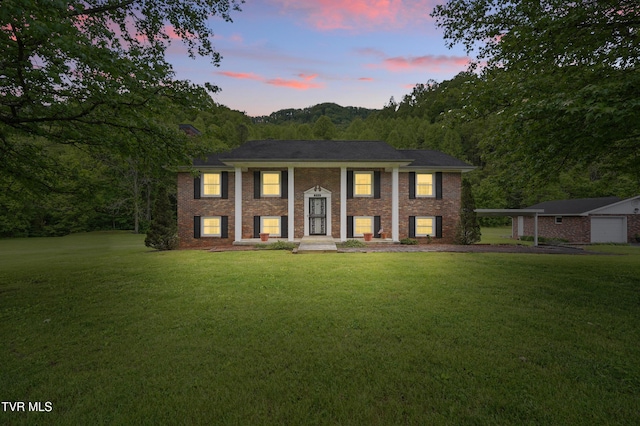 raised ranch featuring a lawn and brick siding