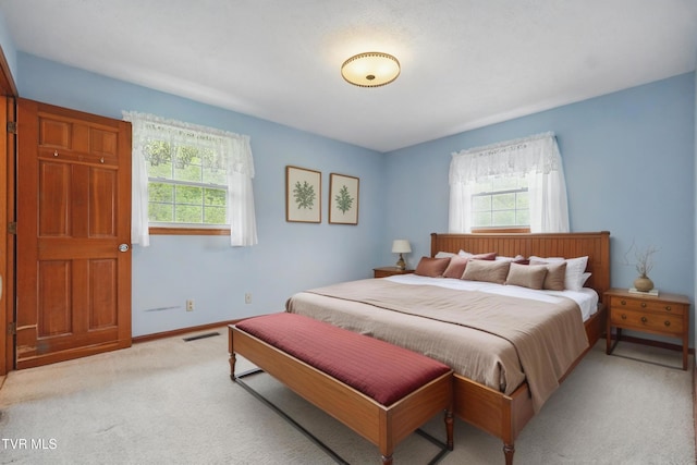 bedroom with multiple windows, light carpet, and baseboards