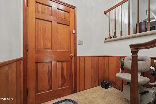 entrance foyer with a wainscoted wall, carpet, and wooden walls