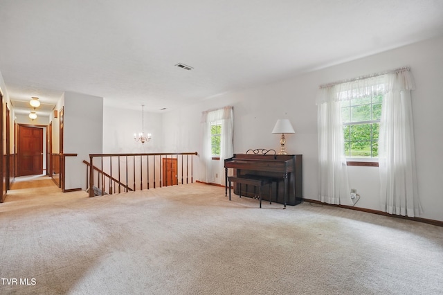 sitting room with an upstairs landing, plenty of natural light, a chandelier, and carpet