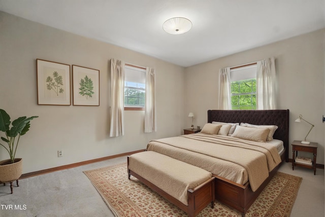 bedroom featuring multiple windows, light carpet, and baseboards