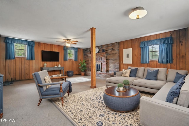carpeted living area featuring wooden walls, a ceiling fan, and healthy amount of natural light