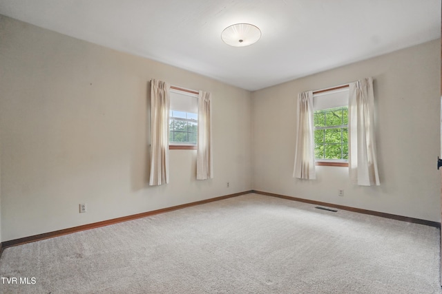 unfurnished room featuring healthy amount of natural light, carpet floors, and baseboards