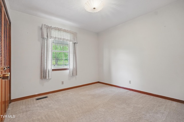 spare room with light colored carpet and baseboards