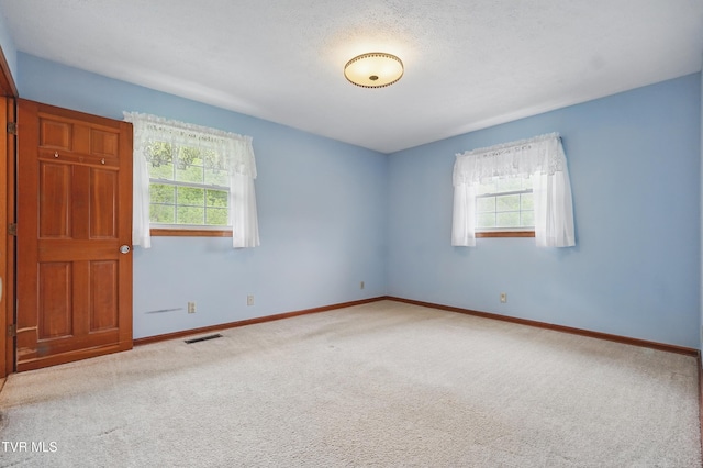 carpeted empty room featuring plenty of natural light and baseboards