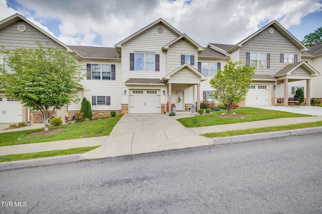 multi unit property with driveway, a garage, and stone siding