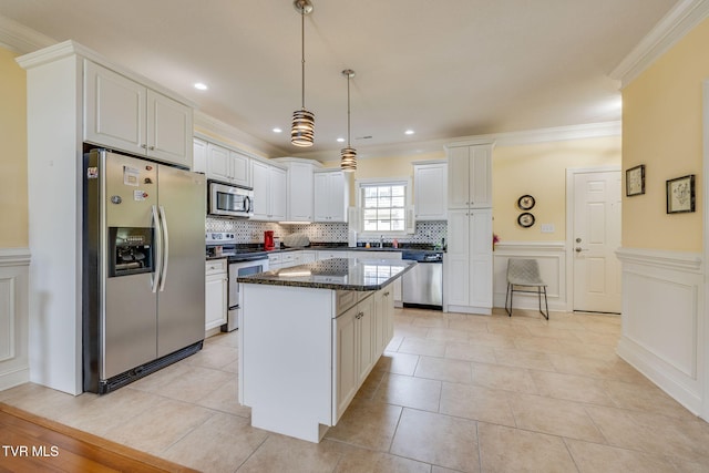 kitchen featuring stainless steel appliances, ornamental molding, a center island, tasteful backsplash, and white cabinets