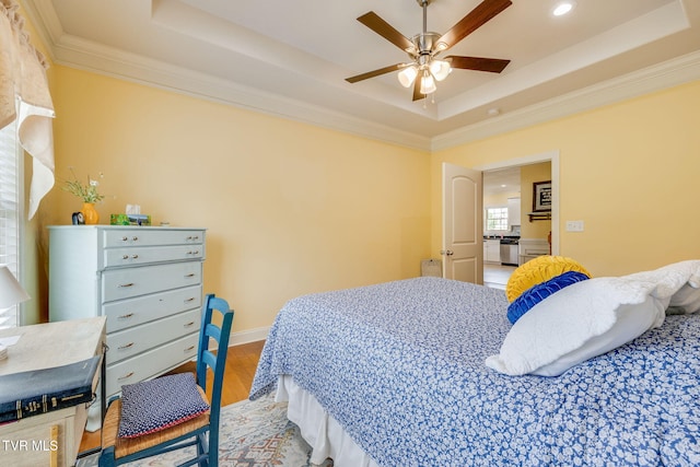 bedroom featuring a tray ceiling, light wood-style flooring, crown molding, recessed lighting, and a ceiling fan