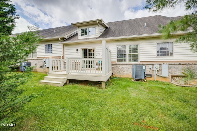 rear view of house with cooling unit, brick siding, a deck, and a yard