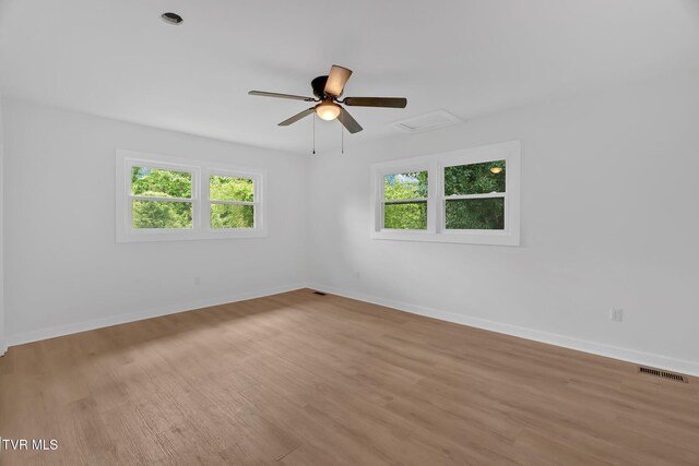 spare room with wood finished floors, baseboards, a ceiling fan, and attic access